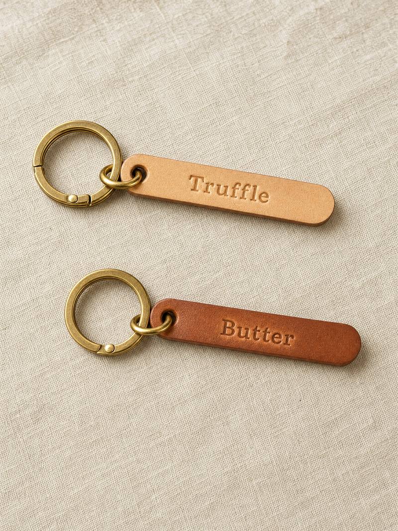 Two personalised leather keychains on brass rings, pressed Truffle and Butter